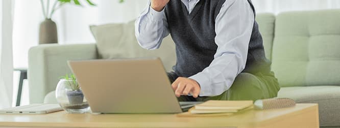 PCを開き電話をする男性画像